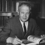 ภาพเงาของยานลงจอดบลู โกสต์ บนพื้นผิวดวงจันทร์ที่เต็มไปด้วยหลุมอุกกาบาต และโลกปรากฏเป็นลูกกลมเรืองแสงอยู่เหนือขอบฟ้า