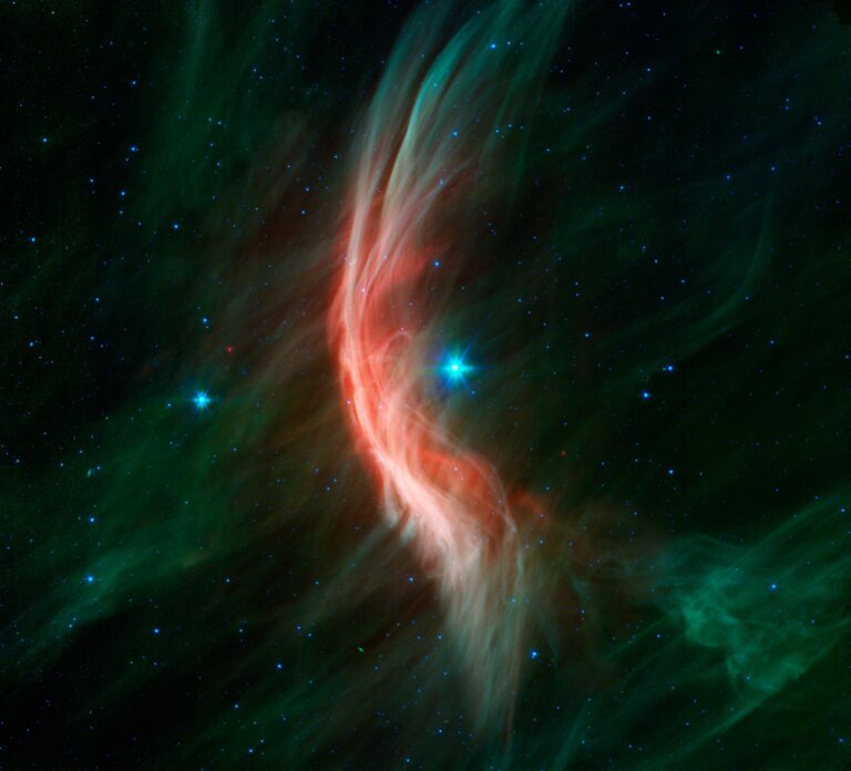 The giant star Zeta Ophiuchi is having a "shocking" effect on the surrounding dust clouds in this infrared image from NASA’s Spitzer Space Telescope. Stellar winds flowing out from this fast-moving star are making ripples in the dust as it approaches, c